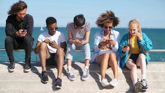 朋友们坐在海边各自玩手机