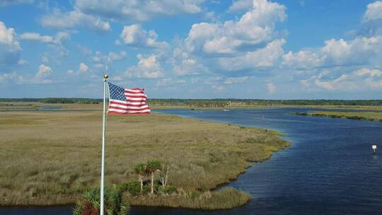 航拍在河流沼泽边飘扬的国旗