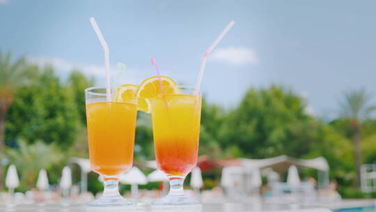 橙色鸡尾酒放在泳池边的沙滩桌上