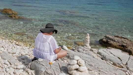 希腊帕拉利亚恩普利西石滩上坐着放松的女游客——静态拍摄
