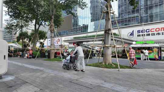 城市商业街老人推轮椅的日常画面