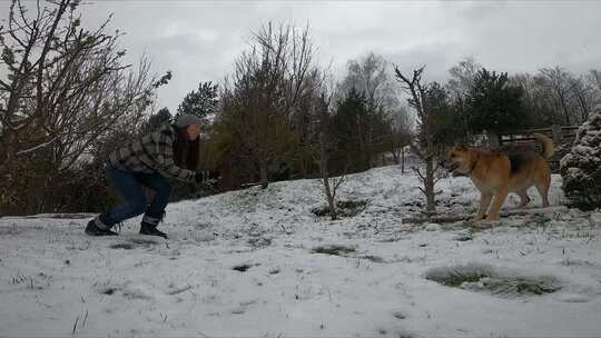 一个在雪地里和她的狗玩耍的女人