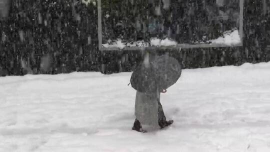 一名打伞的男子在雪地里行走
