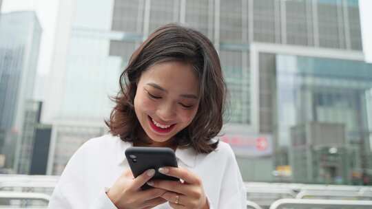 美丽女孩在城市街头看手机短消息刷视频微笑
