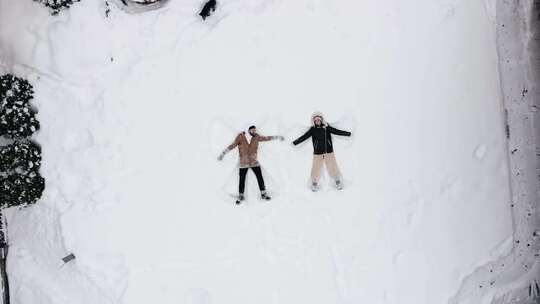 夫妇在外面和他们的狗在雪地上玩耍