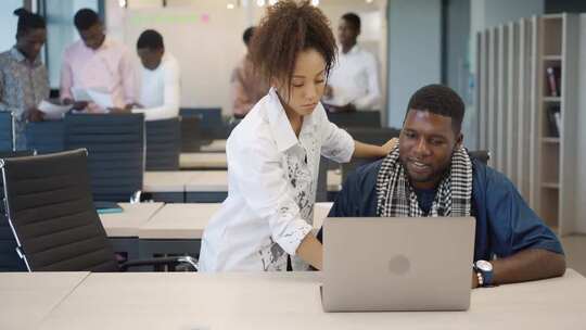 一男一女一边看着笔记本电脑一边互相交谈