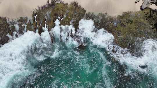 印尼巴厘岛清澈绿松石海水击打礁石溅起浪花