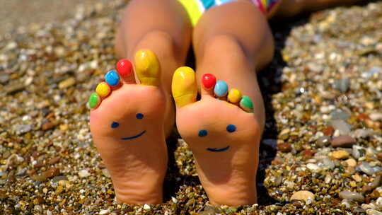 沙滩上小孩可爱的双脚，涂上笑脸