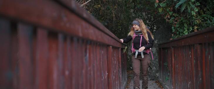 女人背着背包在桥上观赏风景