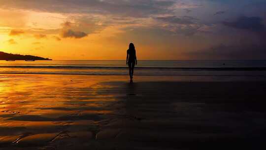 女人走在黄昏的沙滩上剪影