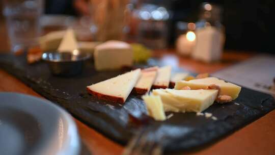 一个人从背景模糊的桌子上的奶酪板上切奶酪