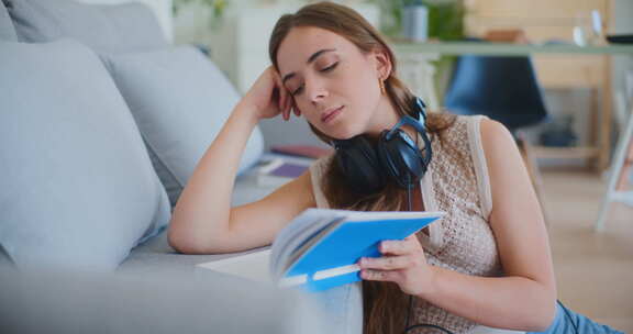 女人合上书本戴上耳机，用音乐放松