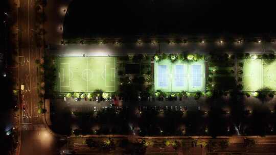 航拍夜间灯火通明的足球场和网球场