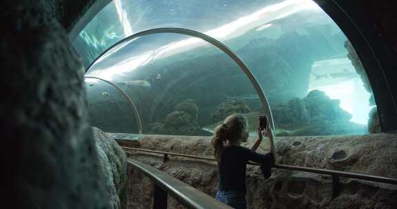 女孩在水族馆给鱼拍照