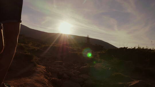 游客在落日的阳光下爬山的剪影