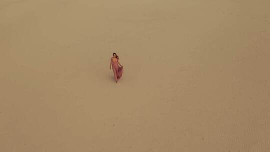 沙漠漫步的鸟瞰图穿着连衣裙的时尚女模