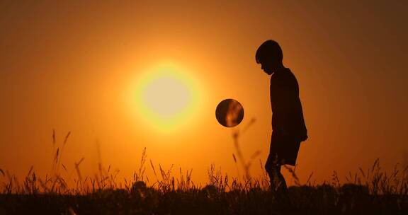 小男孩在夕阳下颠足球