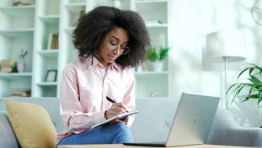 年轻的非裔美国女学生坐着听在线电子学习和
