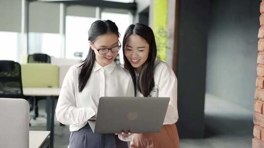 女人看着笔记本电脑，一边微笑一边说话