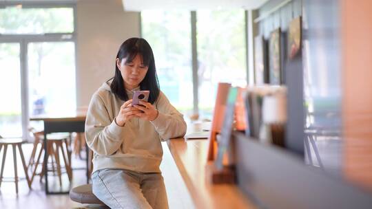 年轻女子在咖啡馆使用智能手机