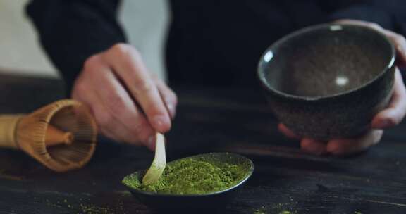 男人将抹茶绿茶粉放入碗中。抹茶有机绿茶。