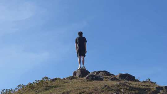 男子山顶站立眺望远方