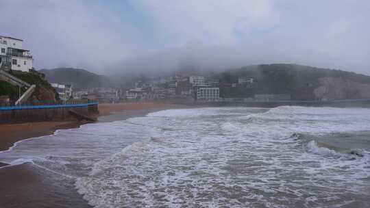 雾中海边小镇景观，海浪拍岸的景象