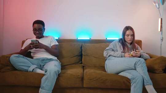 男人和女孩坐在沙发两端玩手机视频素材模板下载