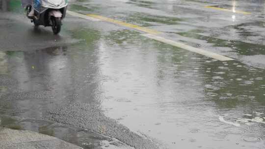 下雨天电动车路过街道积水溅起水花慢镜头