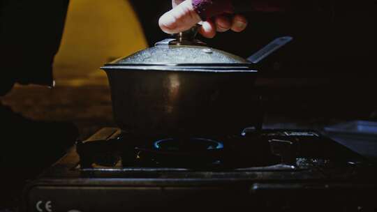 一个人把烹饪锅放在便携式炉子上