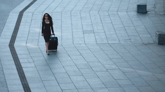 在街上提着行李走路的女人