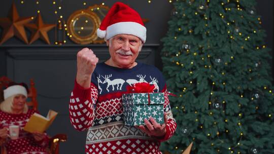 穿着圣诞毛衣的老爷爷做出庆祝成功的手势