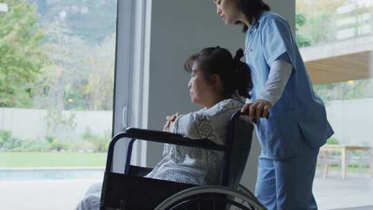 护士推坐轮椅病人看向窗外