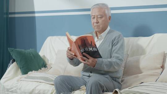 中老年男士客厅沙发上看书阅读学习视频素材模板下载