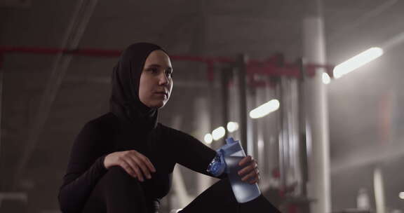 穆斯林女运动员采取休息在健身房