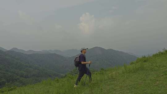 男子山间徒步手持登山杖