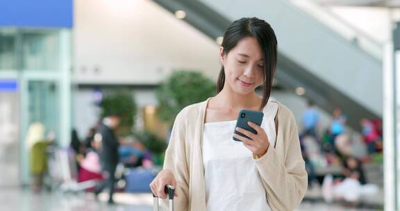 妇女在机场使用智能手机