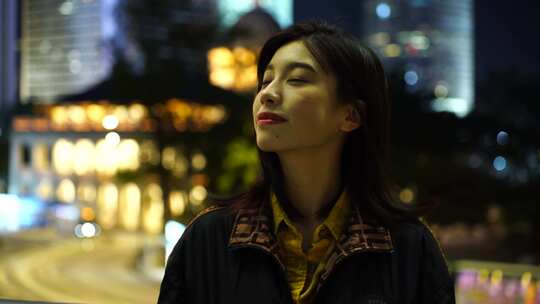 香港街头夜晚面对镜头微笑的女性青年开心笑