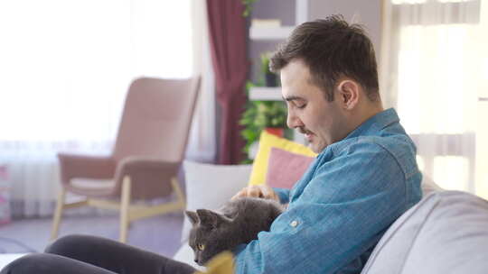 这个男人在家爱他的猫，抚摸着猫的头。