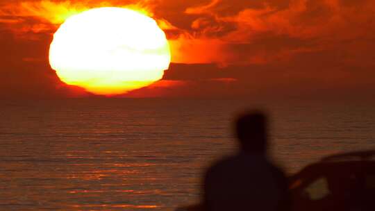 一个男人在海滩上看日落的剪影。