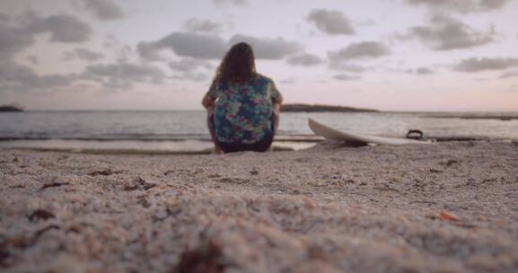 女人坐在沙滩上欣赏风景