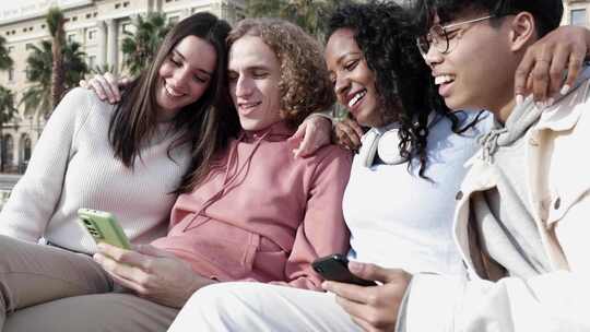一群多种族的年轻朋友在户外使用手机