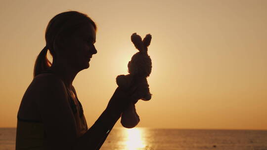 女孩和玩具兔子玩耍的剪影