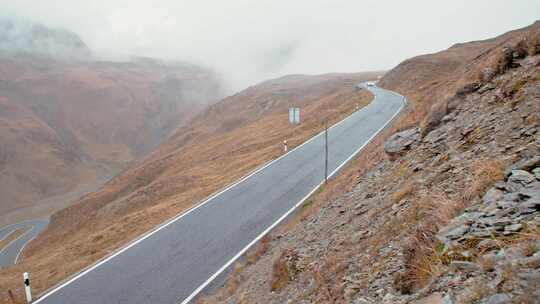 汽车在薄雾环绕的山间蜿蜒的道路上行驶