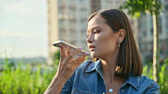 年轻女子在智能手机户外街道城市风格上录制