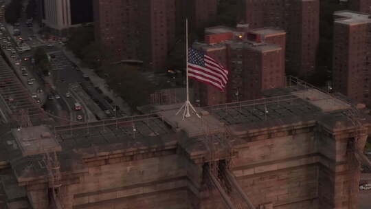 美国航空公司：纽约布鲁克林大桥上空有美国国旗和雾蒙蒙的曼哈顿上空的特写圆圈飞行