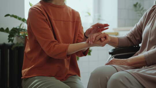 女人在家里坐在轮椅上牵着祖母的手