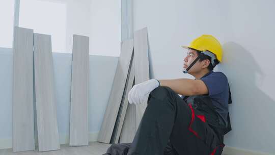 亚裔建筑工人男子感到疲惫，下班后躺在地板上装修房子。