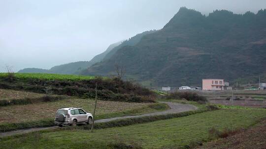 乡下农村土路慢行的车辆崇山峻岭里小县城