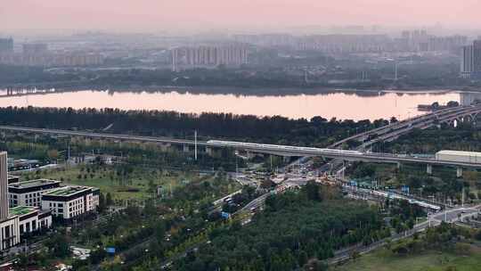 航拍夕阳高铁行驶桥梁河流车流建筑群高楼